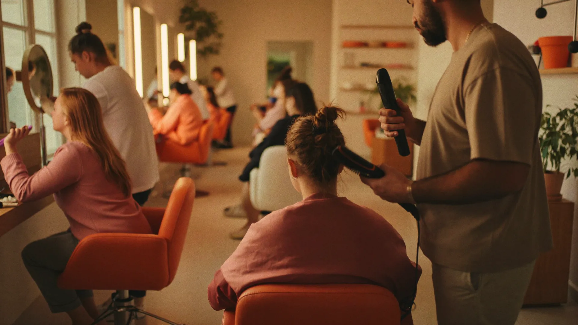 Kapper föhnt het haar van een klant in een warme, drukke kapsalon